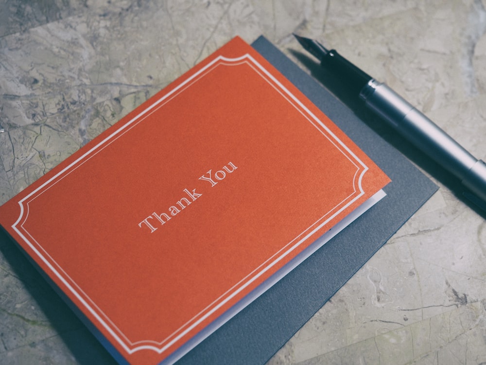 Fountain pen resting beside a red thank-you card