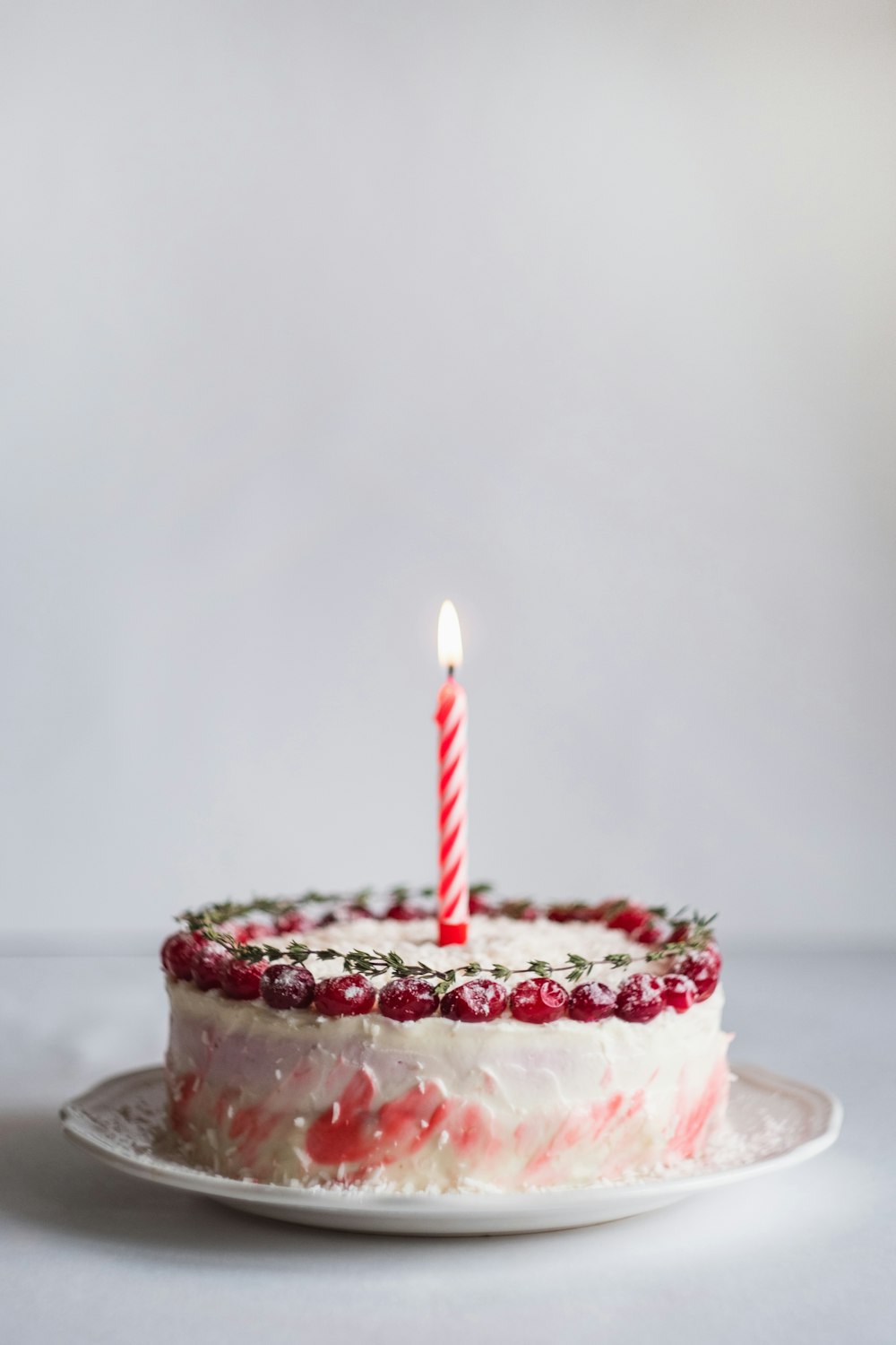 White and pink birthday cake with a lit candle