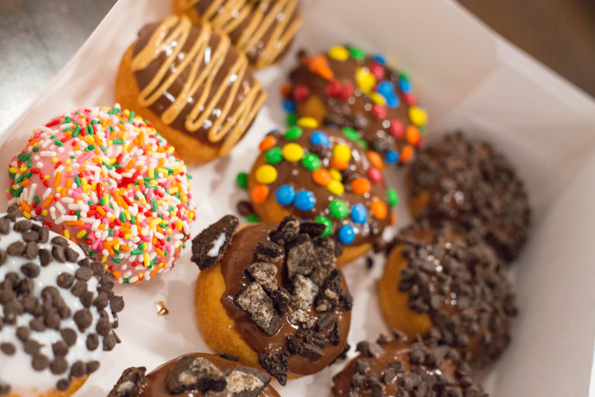 Open box of assorted decorated birthday donuts