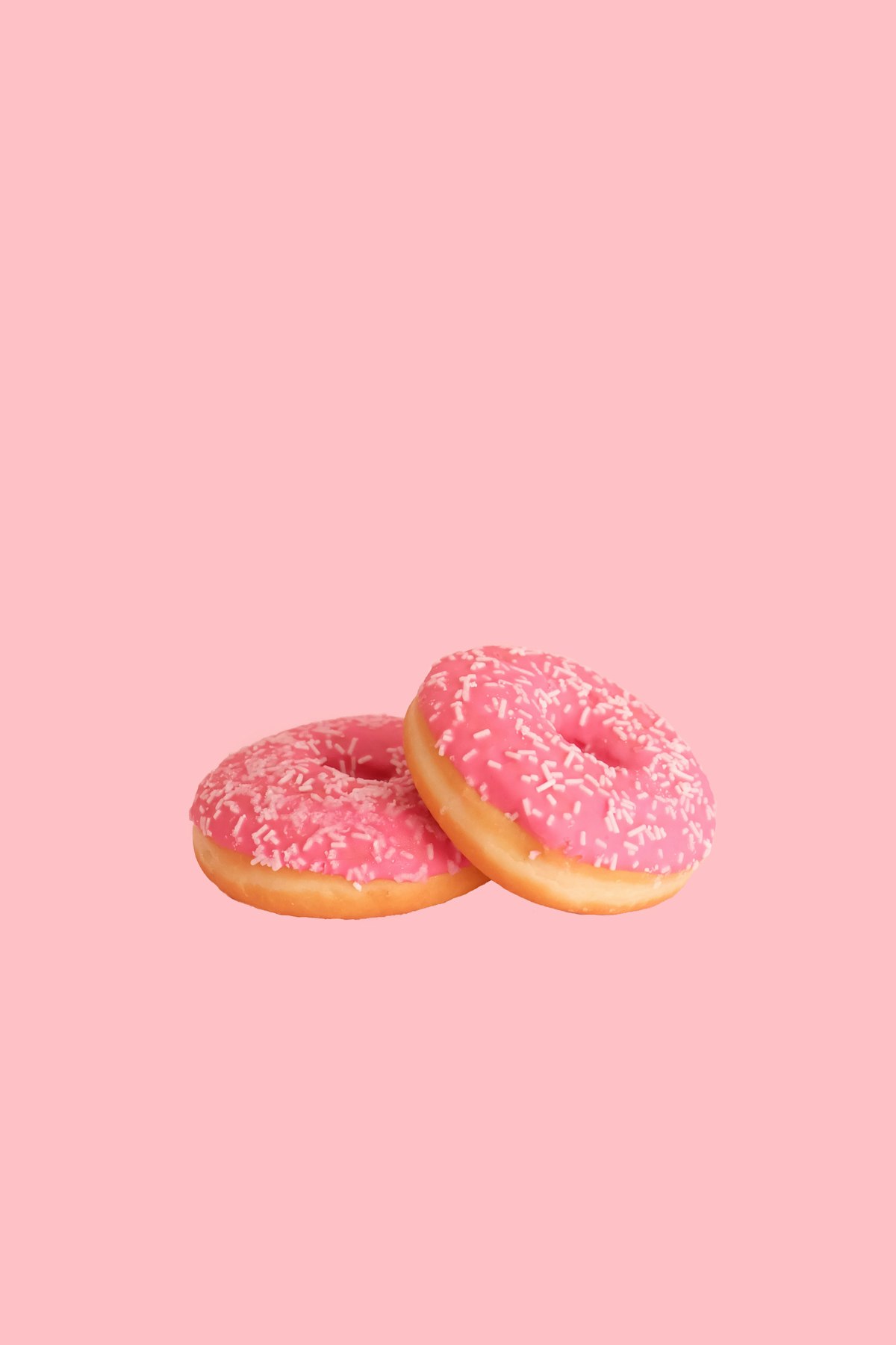 Two strawberry-frosted doughnuts with sprinkles