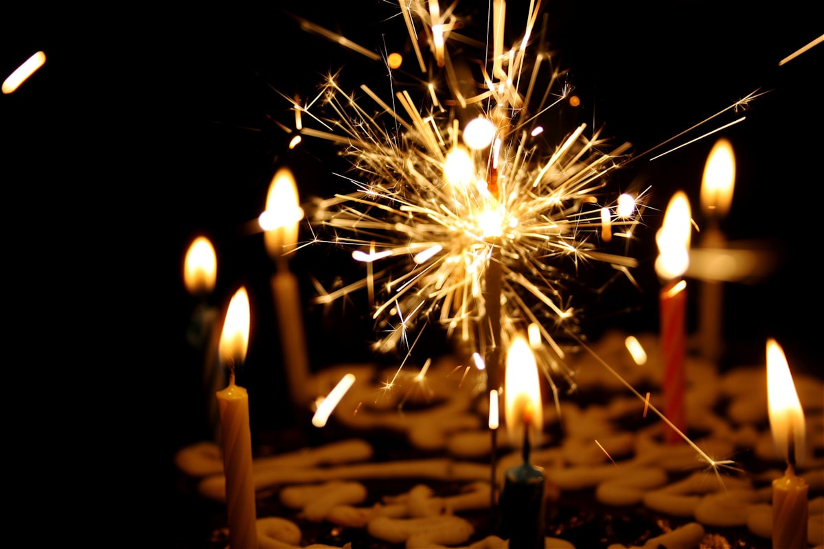 Lit sparkler beside birthday candles marking a milestone celebration