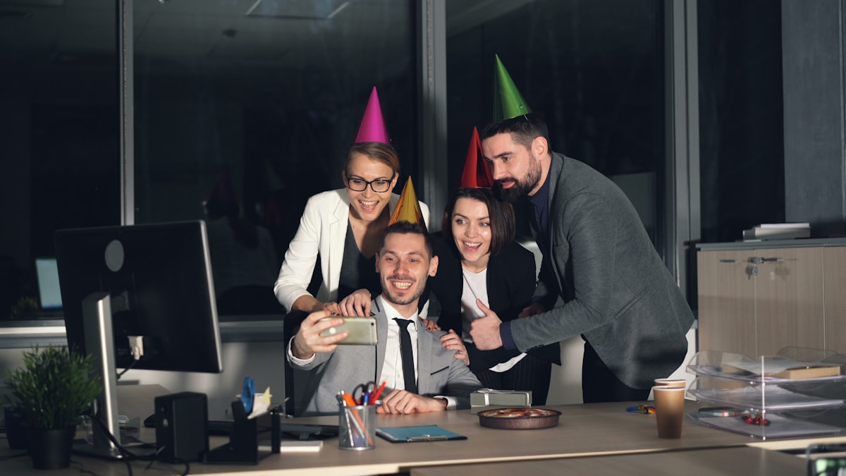 Coworkers taking a selfie at an office birthday party